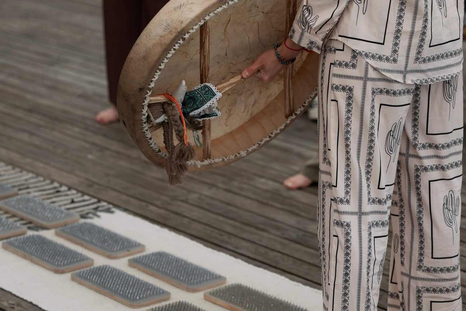 Person holding a traditional drum on a wooden floor