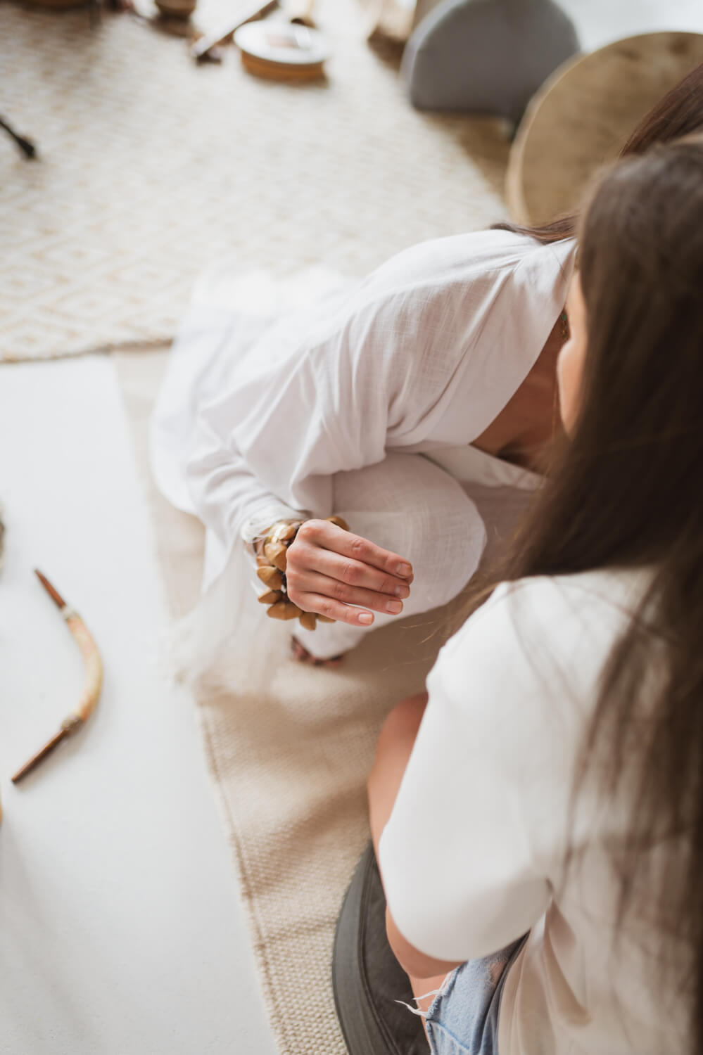 Two people sitting on the floor in a casual setting with a neutral color palette.
